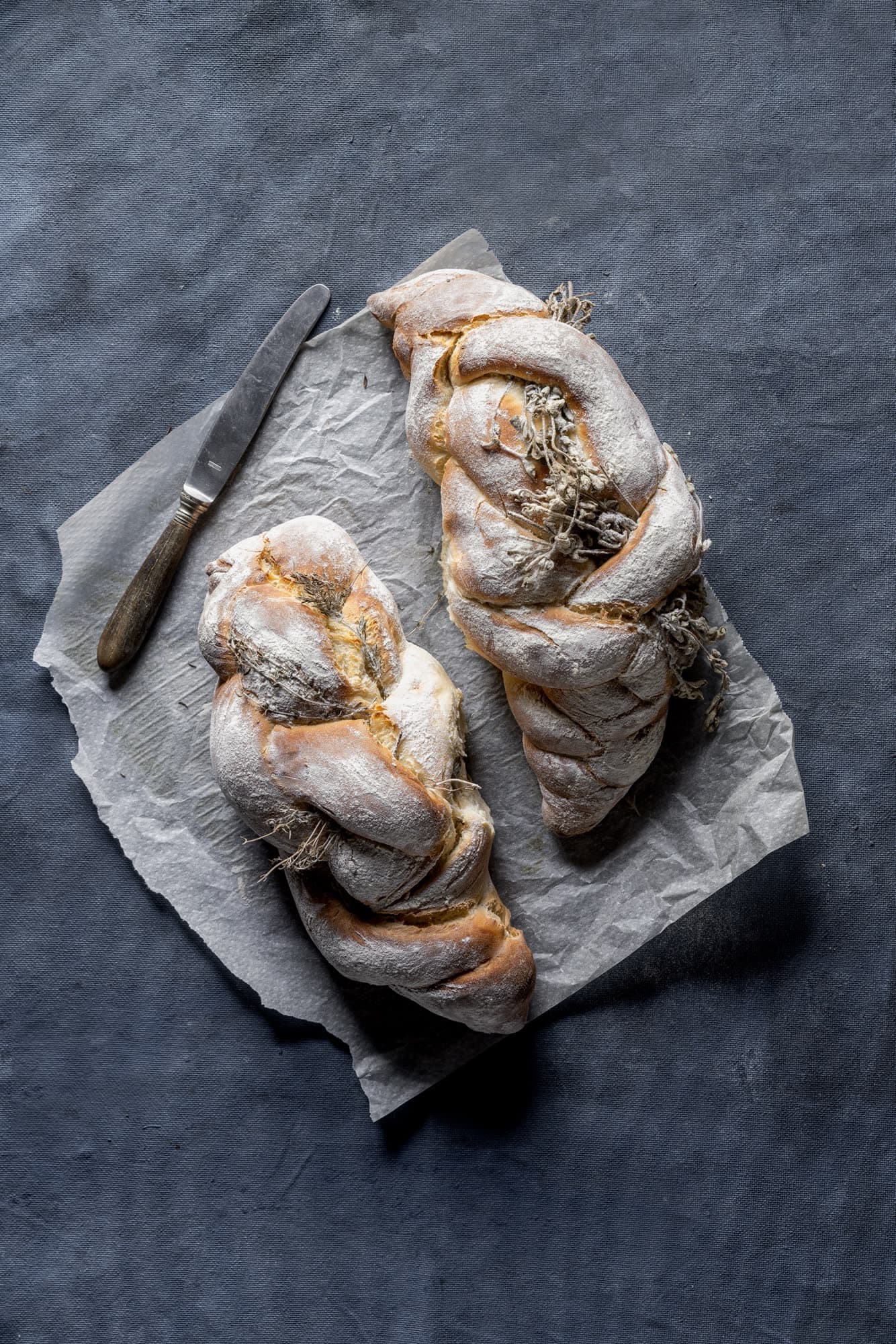 Two braided challot with herbs on baking paper