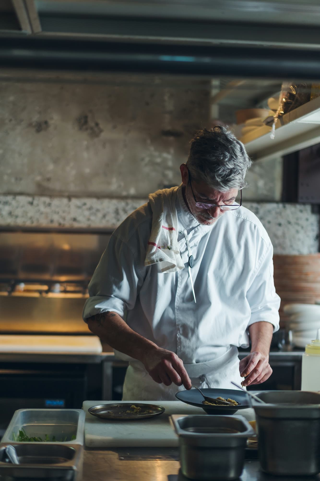 Ohad Amzallag plating a dish in the kitchen